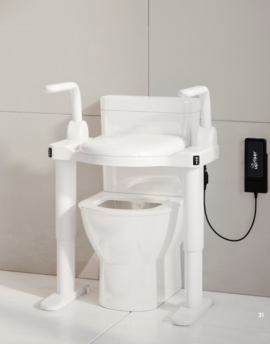 An UpRiser ergonomic powered toilet seat with support arms installed over a toilet in a bright, tiled bathroom